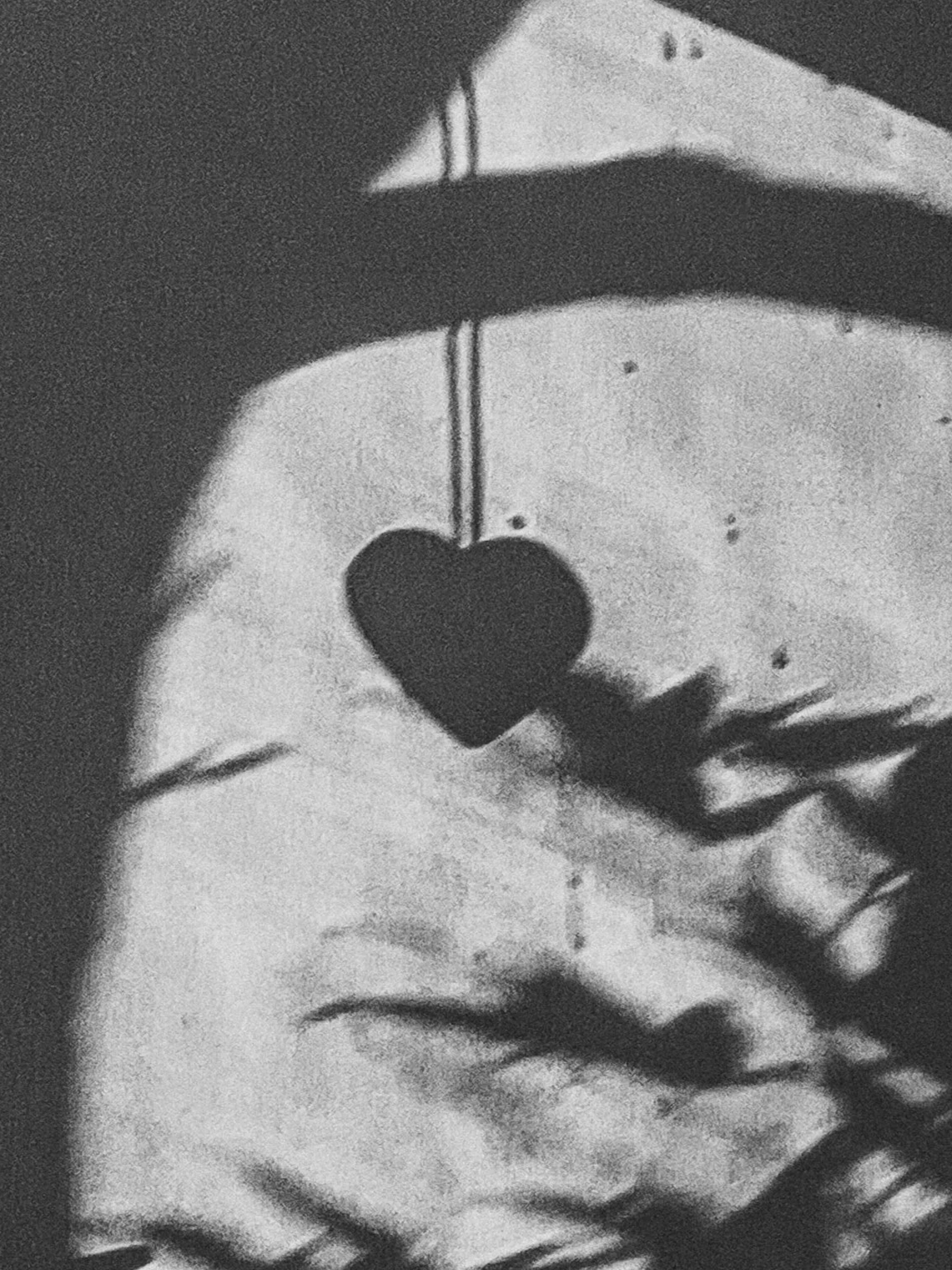 Shadow of a small heart-shaped object on a string.