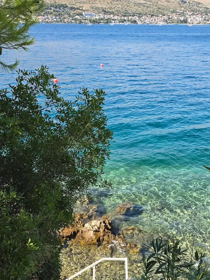 Seaside with pine trees, clear water and beach access combining nature with walking areas, restaurants and local infrastructure