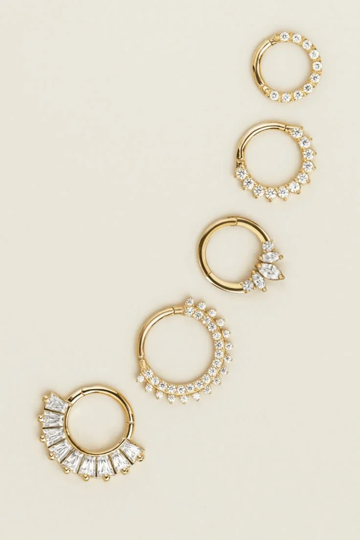 Cinque anelli d'oro decorati con diamanti, disposti in sequenza verticale