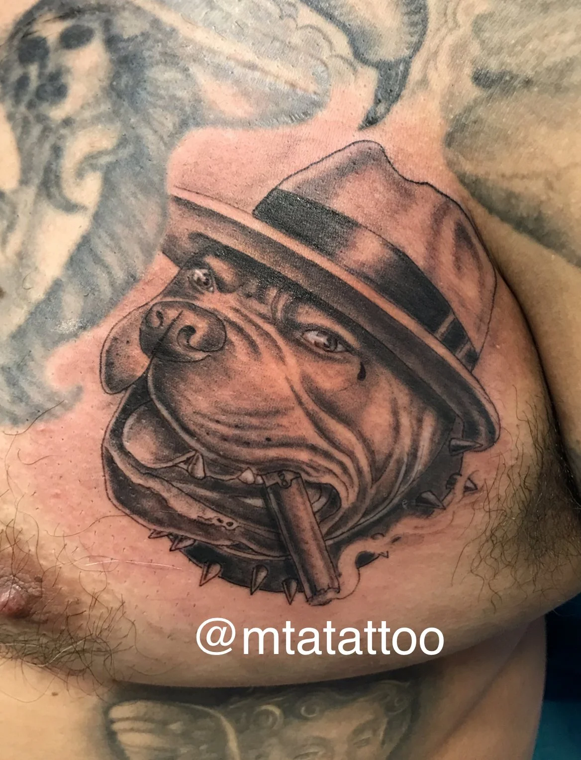 Tatuaggio di un cane con sorriso, con cappello e sigaretta, stile realismo in bianco e nero.
