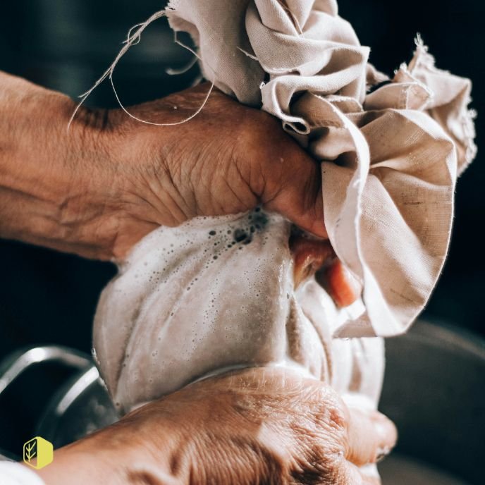 Someone rinsing or squeezing a cloth or bag filled with liquid, likely soap or water, in their hands.