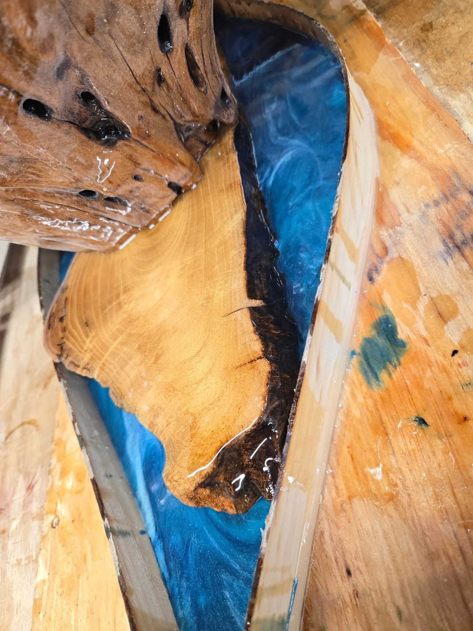 Wooden table with a river-like inlay made of blue and black resin.