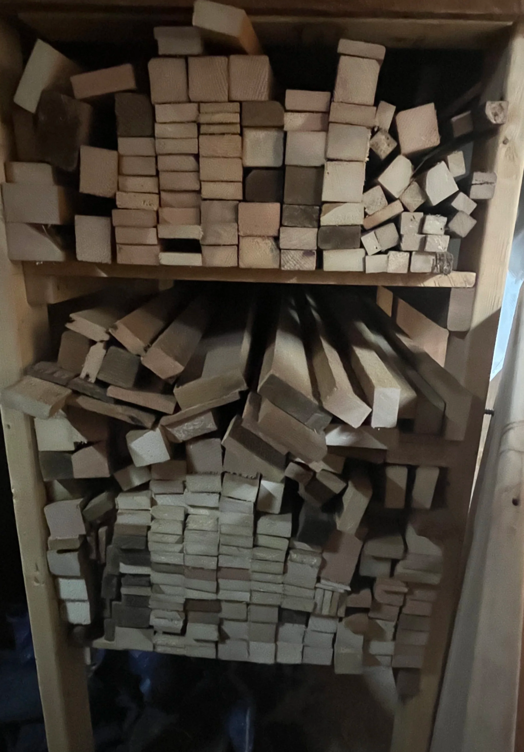 Wooden beams and planks stacked neatly on shelves in a woodworking shop or storage area.