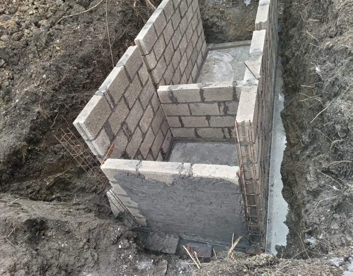 Construcción de una pared de blocks en un hoyo excavado en el suelo.