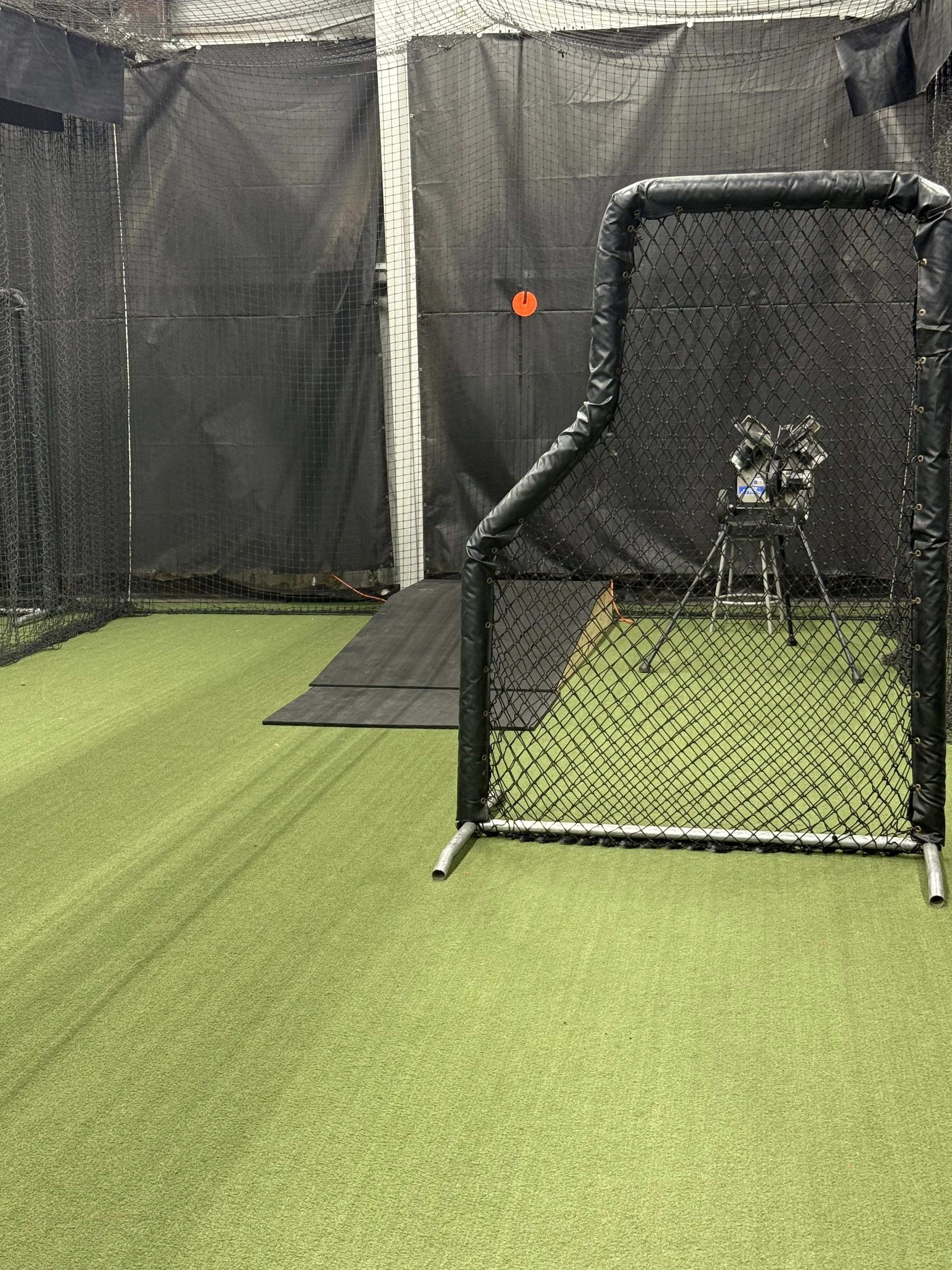 Indoor golf practice area with hitting net, turf, and a golf swing simulator.