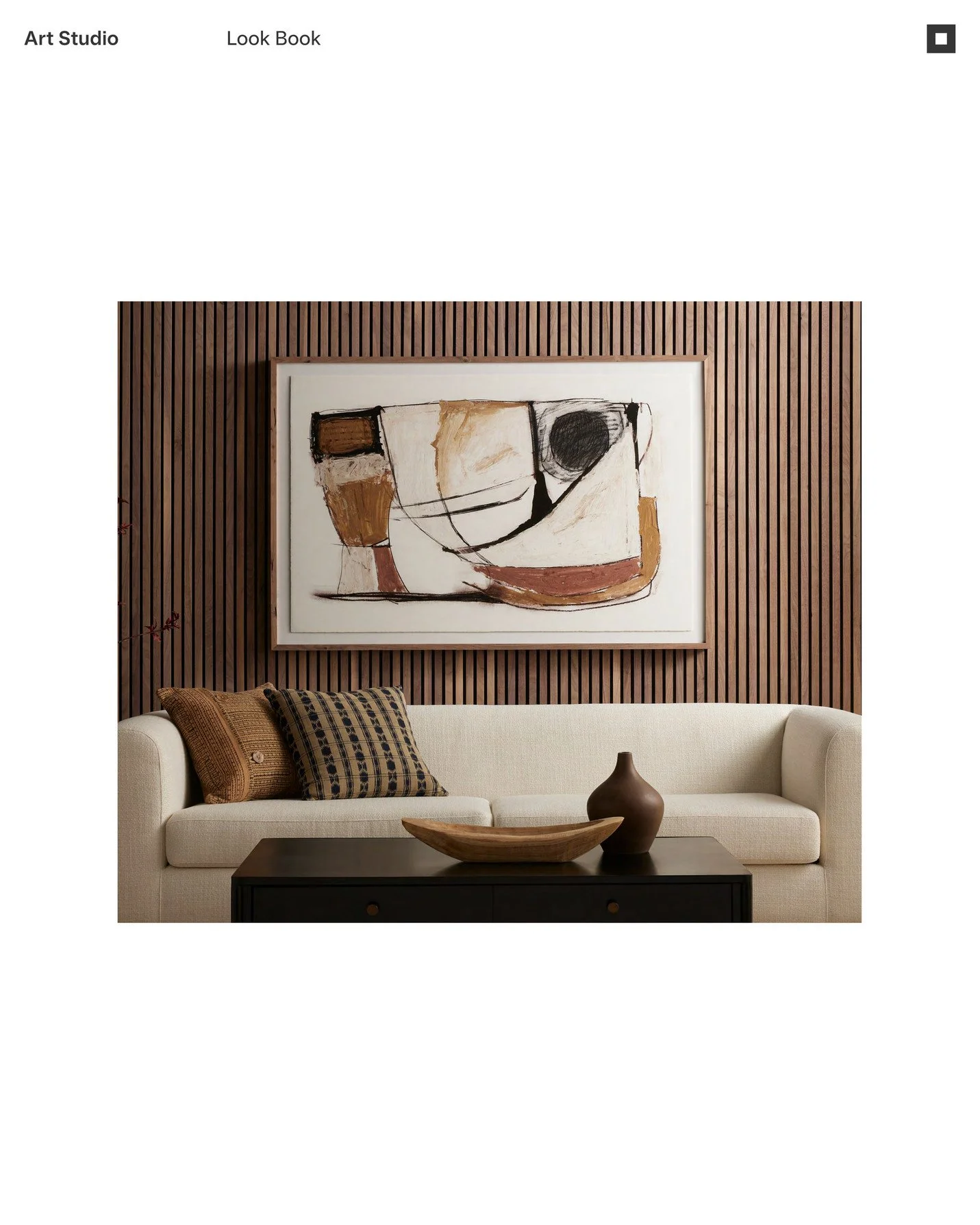 Living room with a white sofa, decorative pillows, wooden wall paneling, abstract artwork, and a dark coffee table with a wooden bowl and ceramic vase.