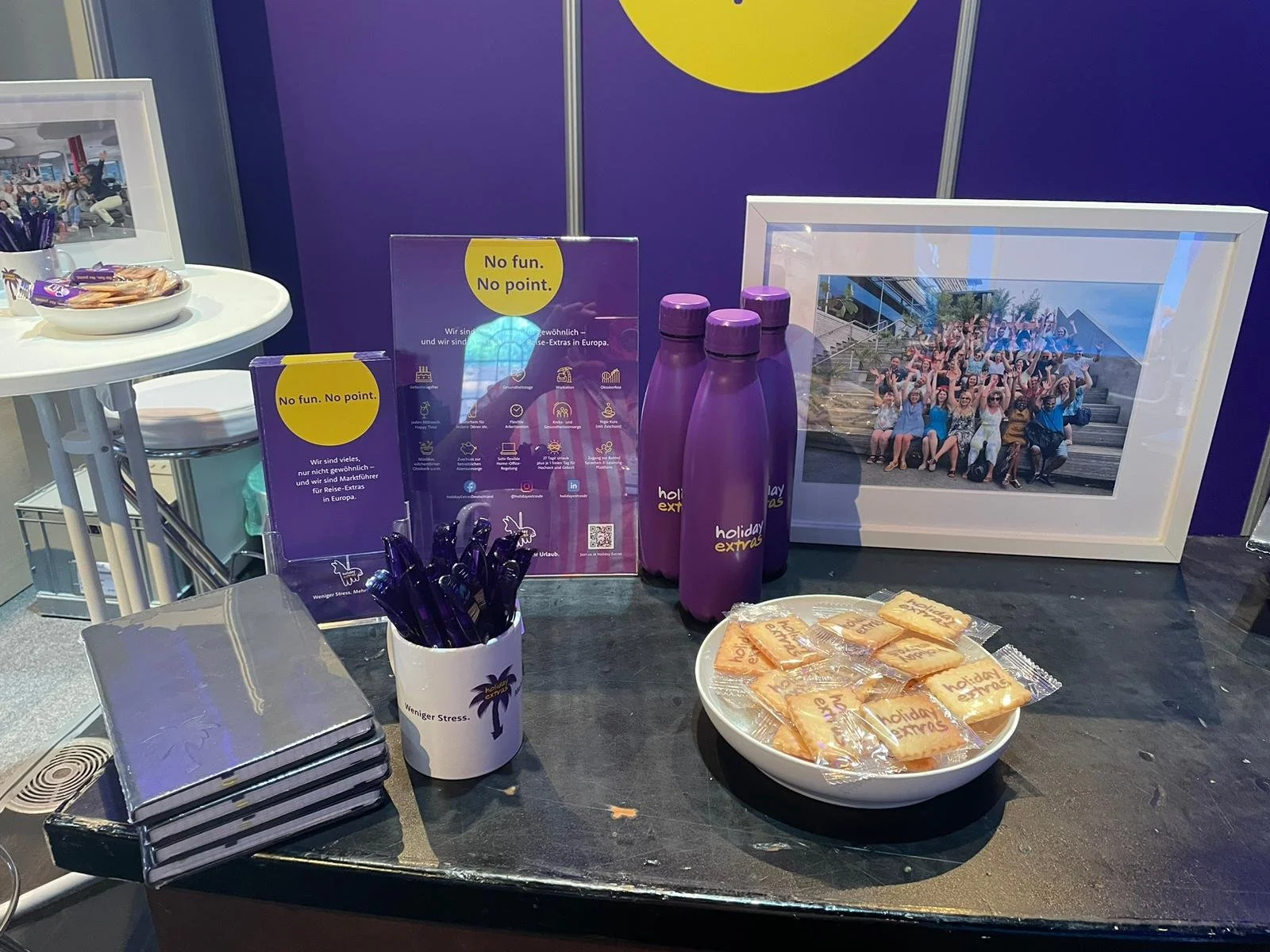 ein Tisch mit Fluggesellschafts-Artikeln wie Wasserflaschen, Brotdosen, Schreibwaren, einem Rahmen mit einem Gruppenfoto, Broschüren und Süßigkeiten, wahrscheinlich auf einer Messe oder einem Event