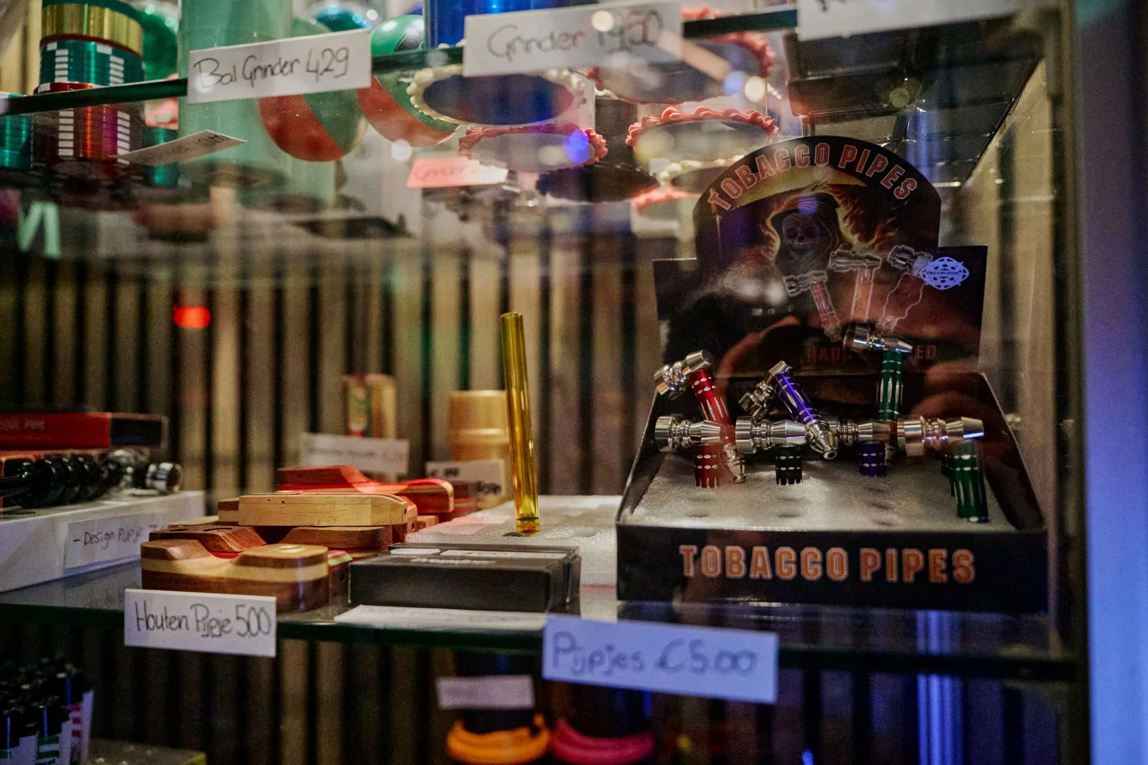 Gedeelte van een winkelrek met tabaksproducten en accessoires, waaronder rookpijpen en houten pijpjes, met prijzen en labels in het Nederlands.