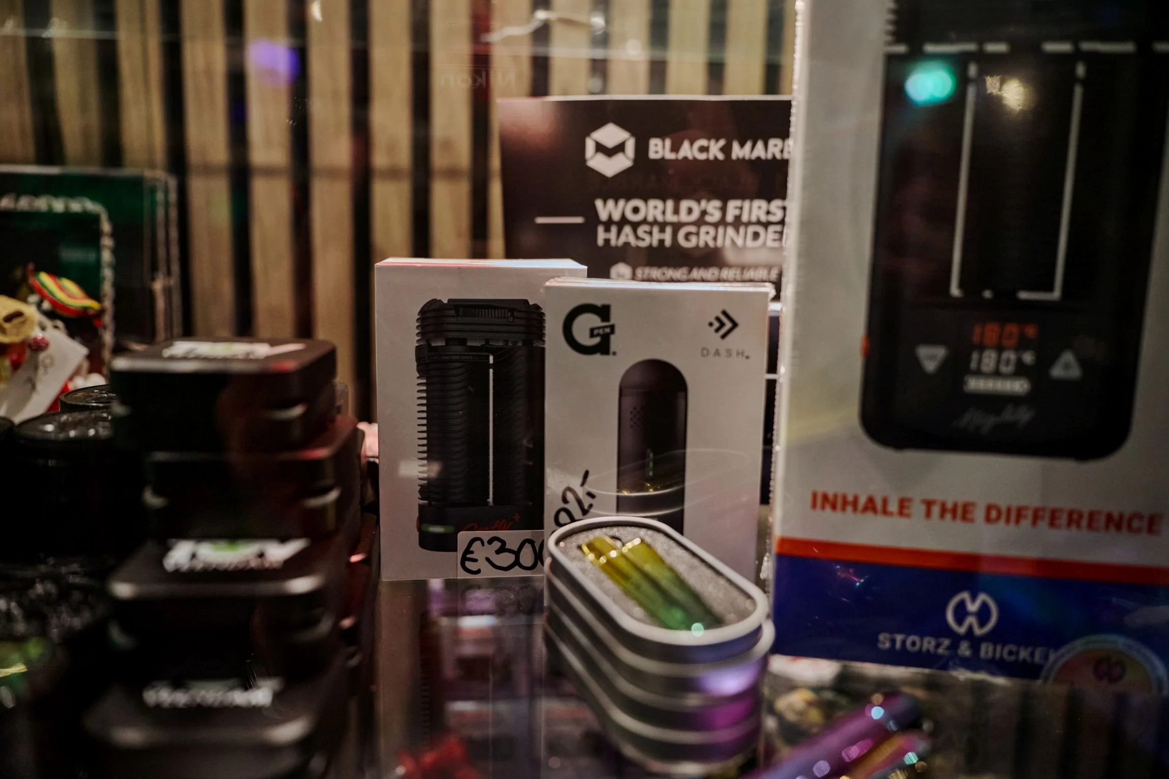 Verschillende cannabis-gerelateerde producten en accessoires op een tafel, inclusief een hash grinder en vape apparaten.