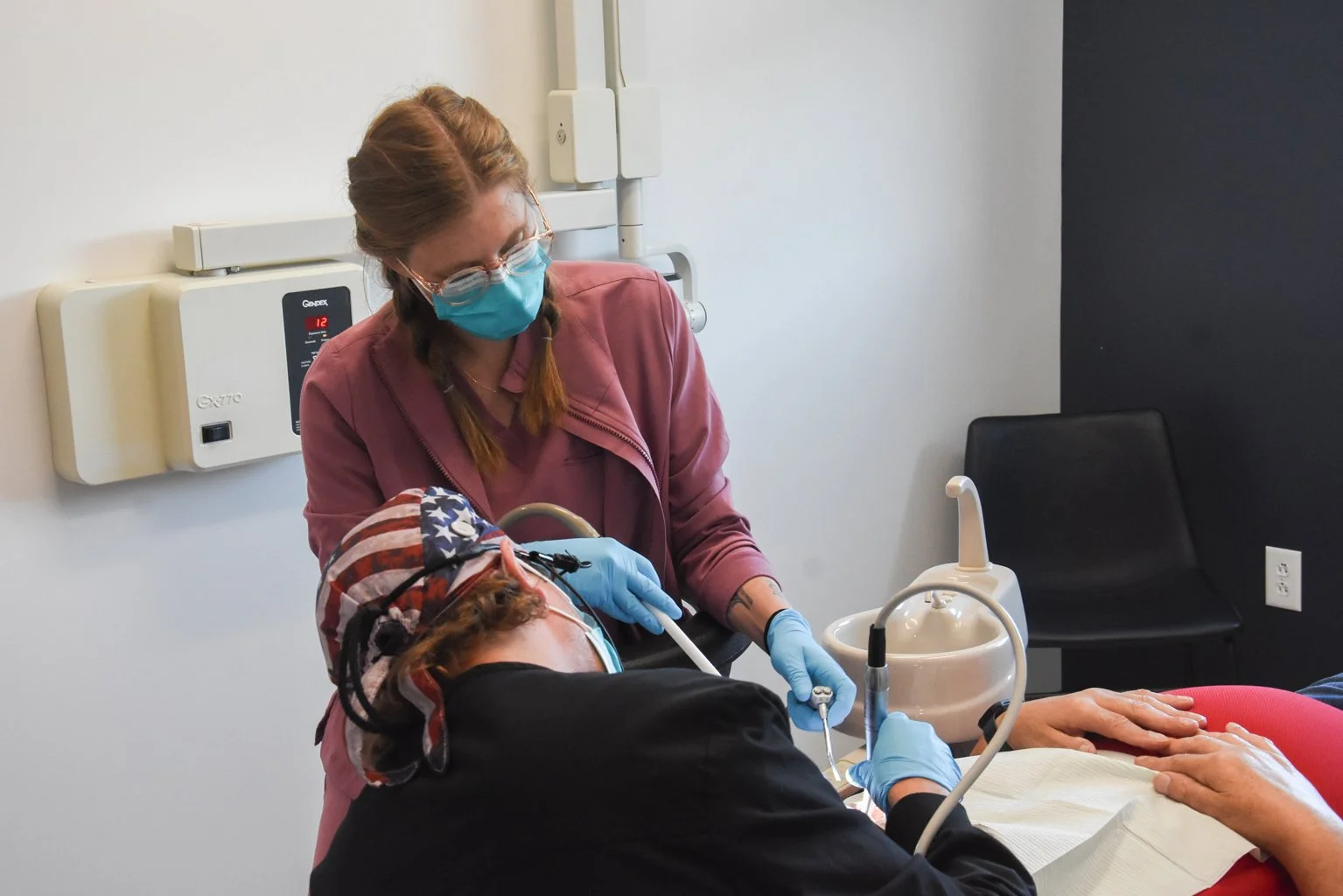 A dentist wearing a mask and gloves performing a dental procedure on a patient in a dental office.