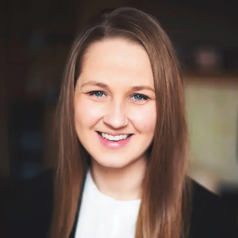 A young woman with long brown hair and blue eyes smiling at the camera.