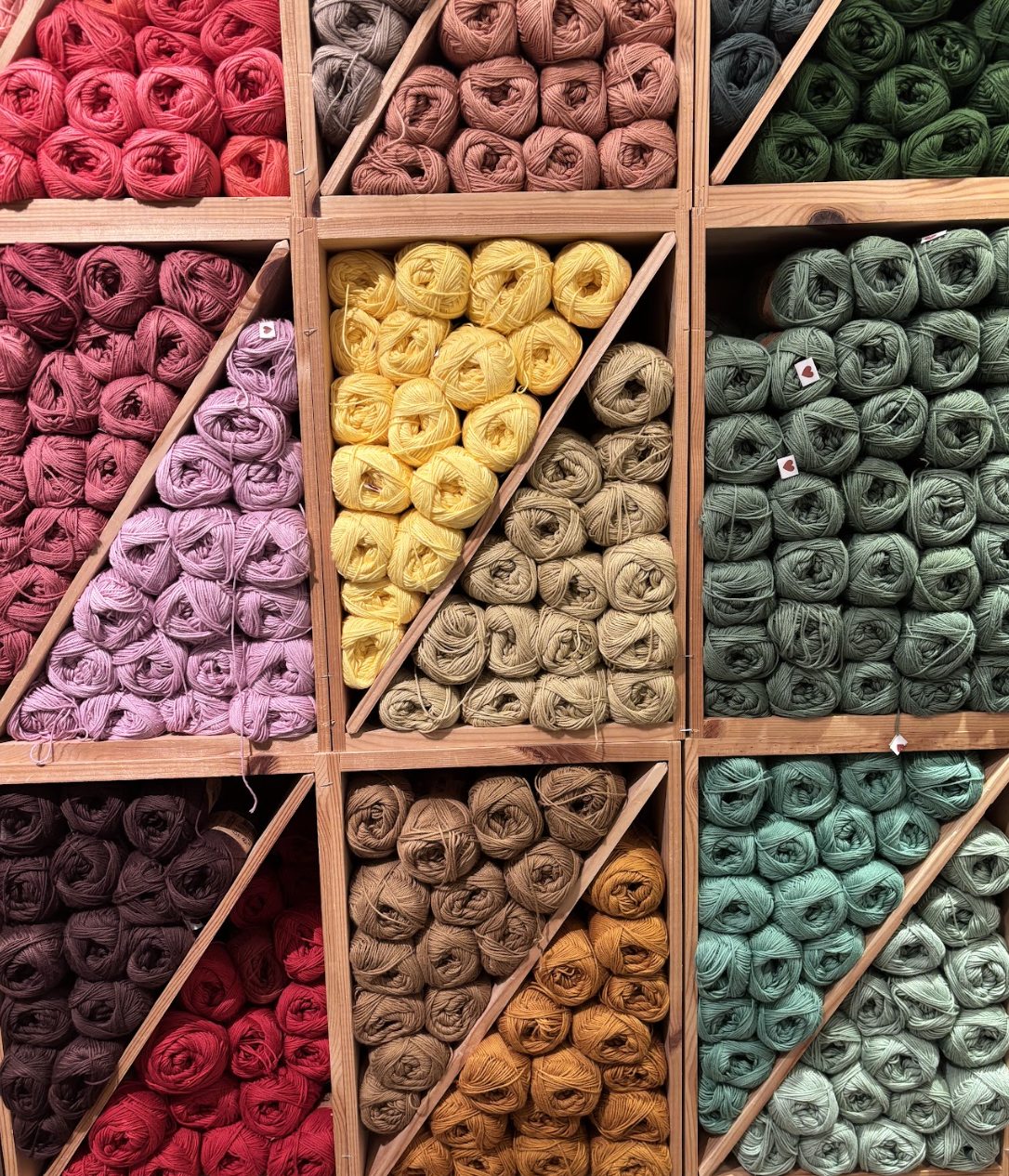 Colorful yarn balls arranged in wooden shelves with diagonal dividers.