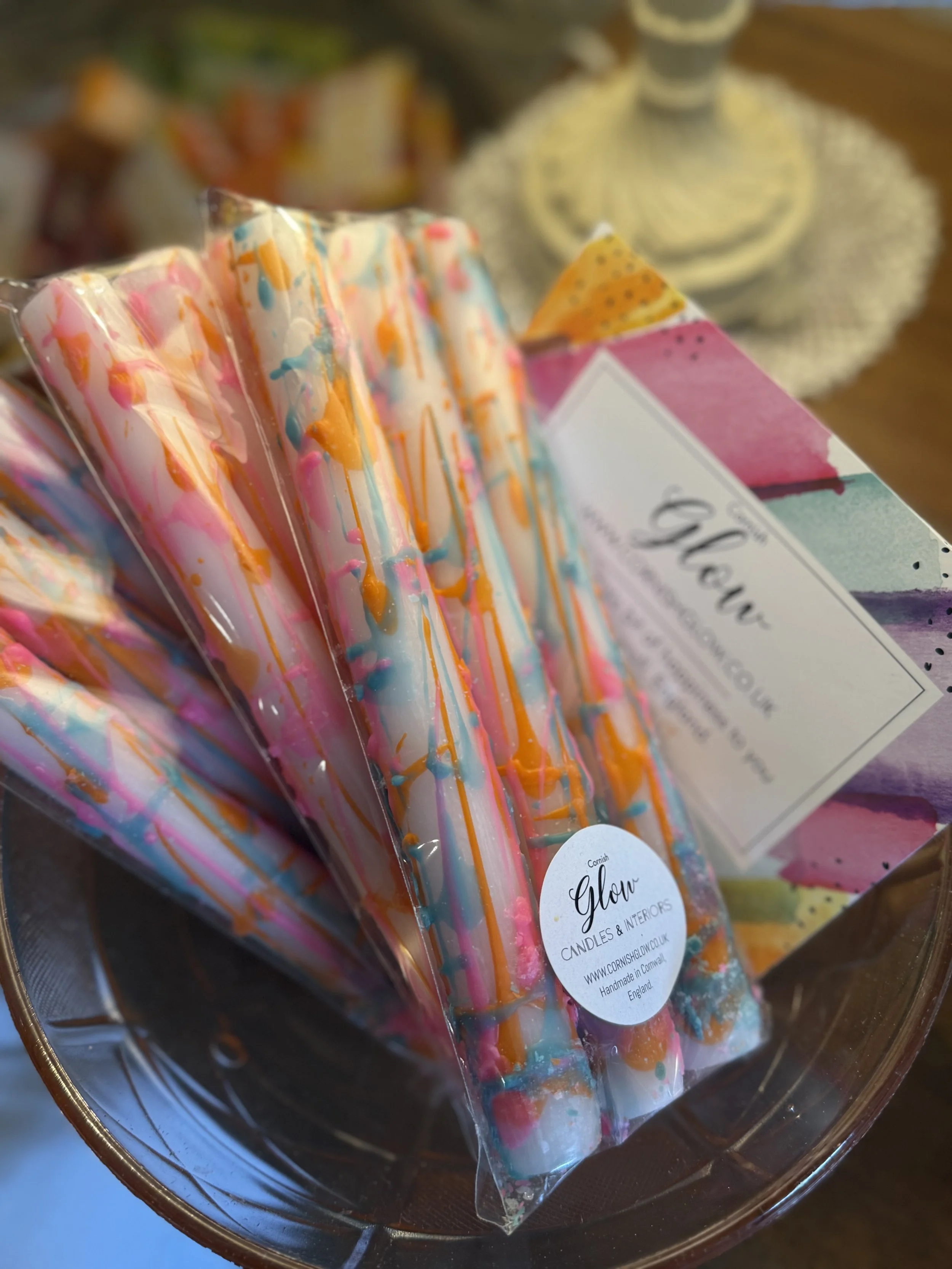 Colorful drip candles wrapped in plastic on a decorative tray.