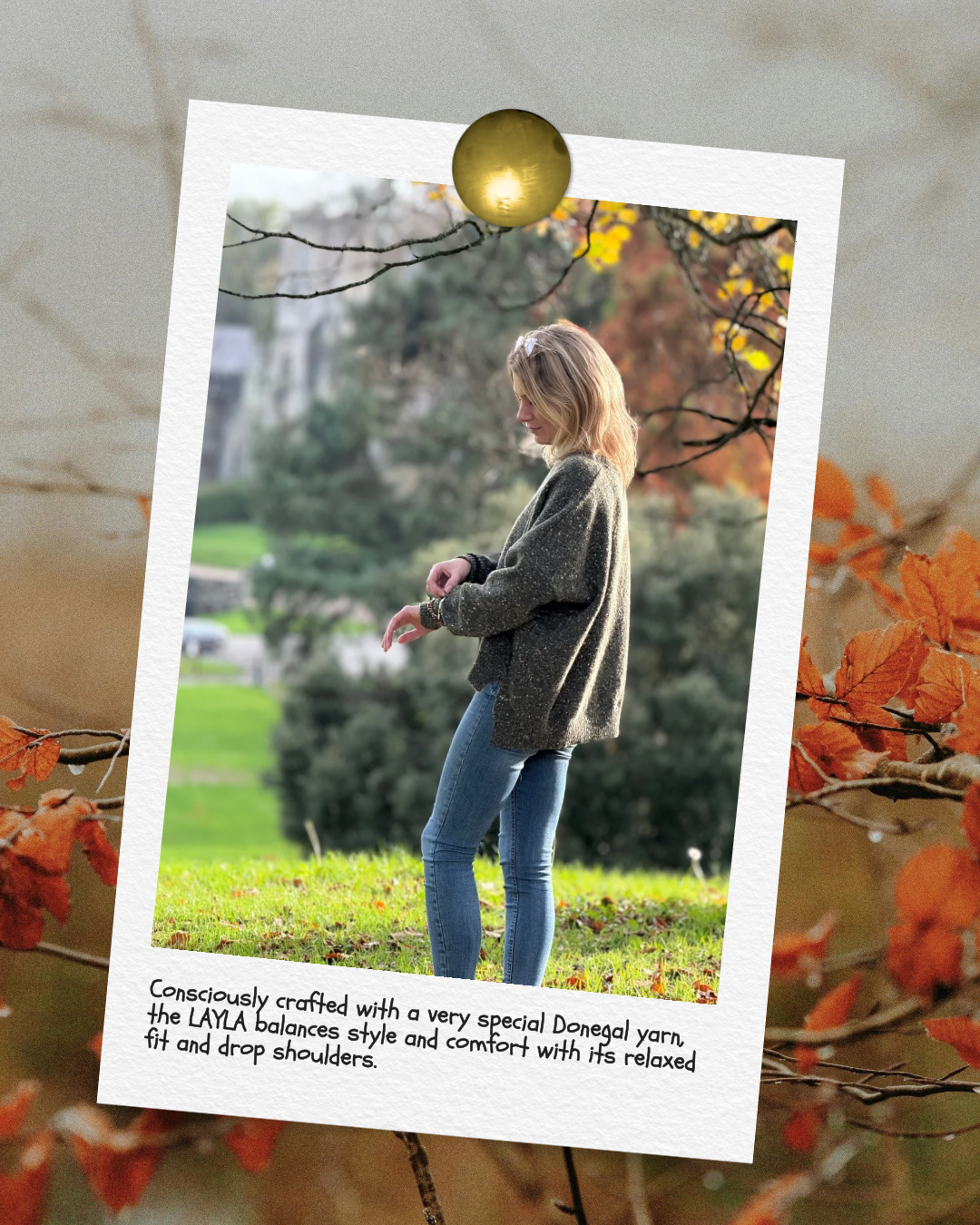A woman standing outdoors in a park during autumn, looking down at her wrist. She is wearing a gray sweater and blue jeans, with trees and fall foliage in the background. The image is presented as a polaroid with a handwritten note.