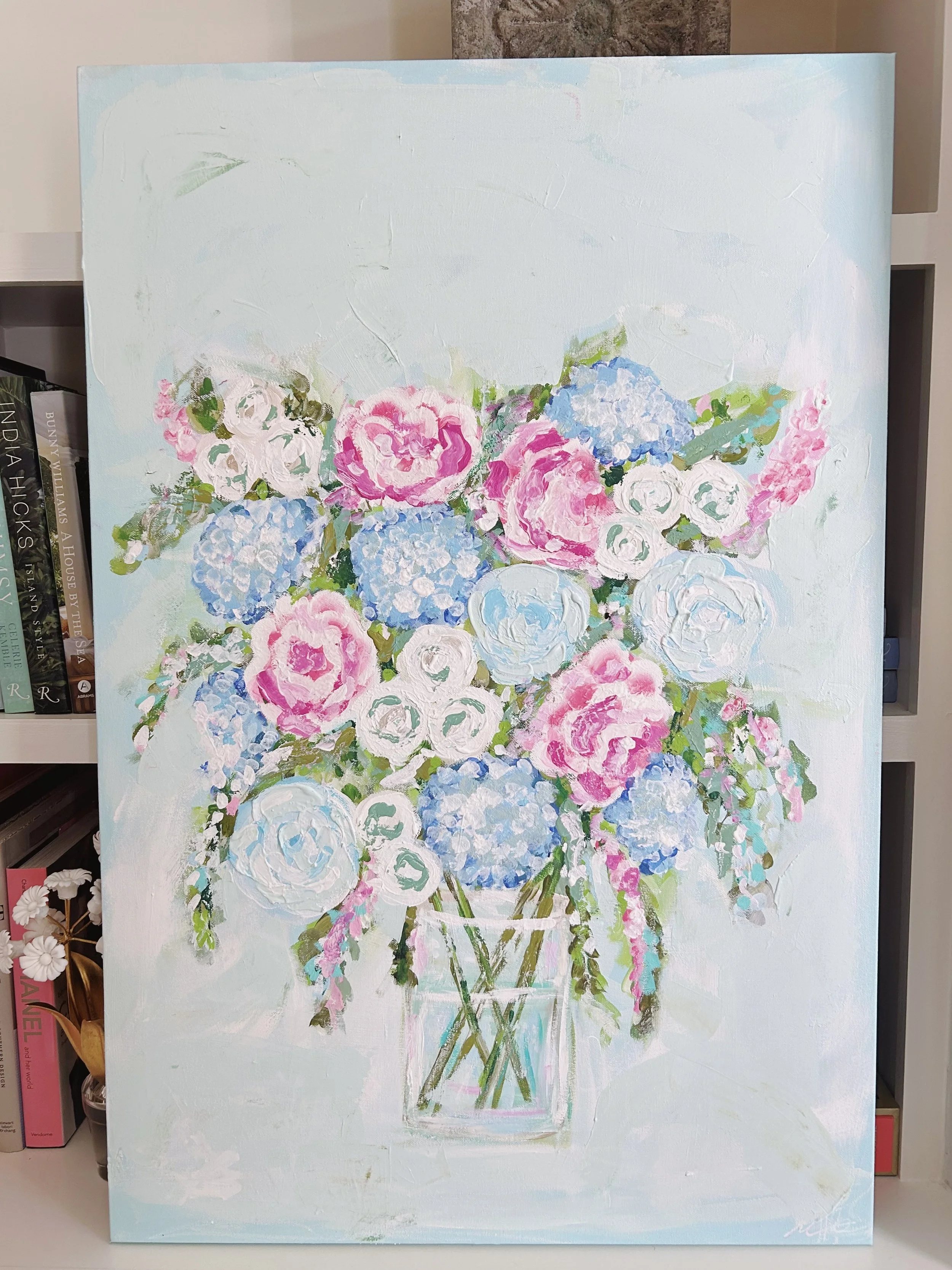 A painting of a bouquet of pink and white roses and blue hydrangeas in a clear glass vase, on a light background.