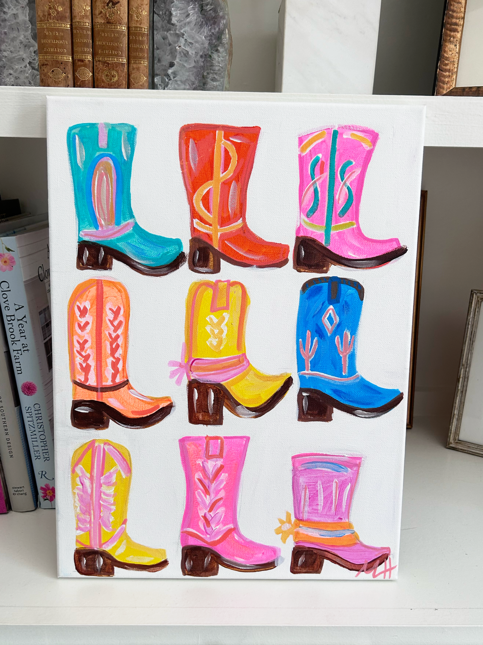 Colorful painting of nine cowboy boots in bright pink, blue, orange, yellow, and teal, arranged in three rows on a white canvas.