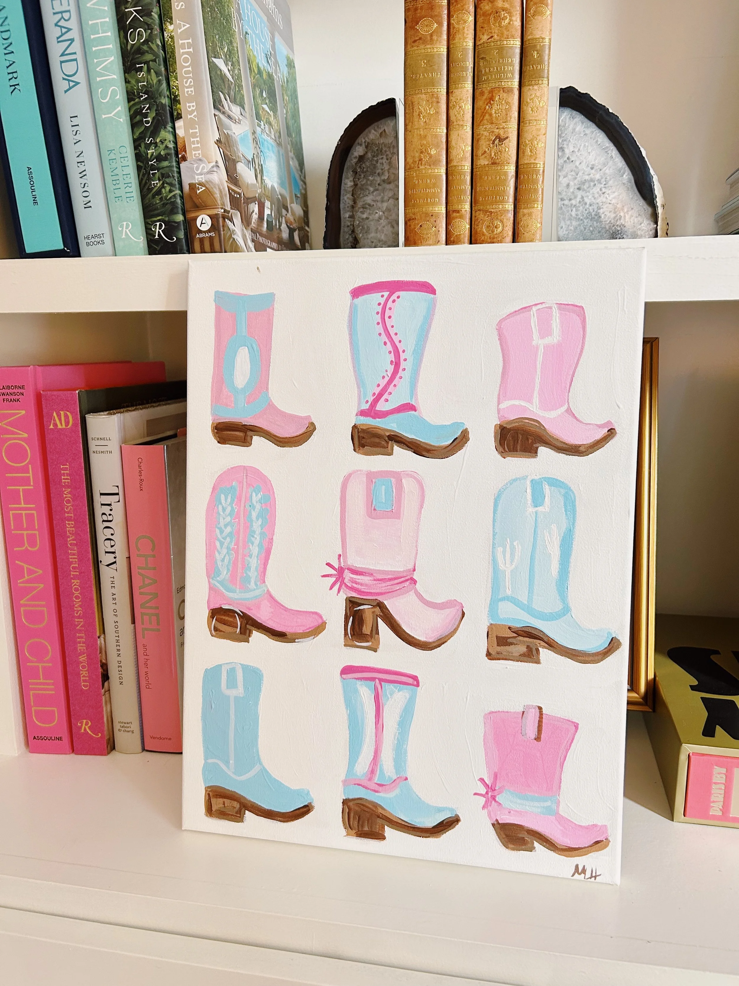A colorful painting of nine cowboy boots, each with different patterns and colors, leaning against a bookshelf filled with books.