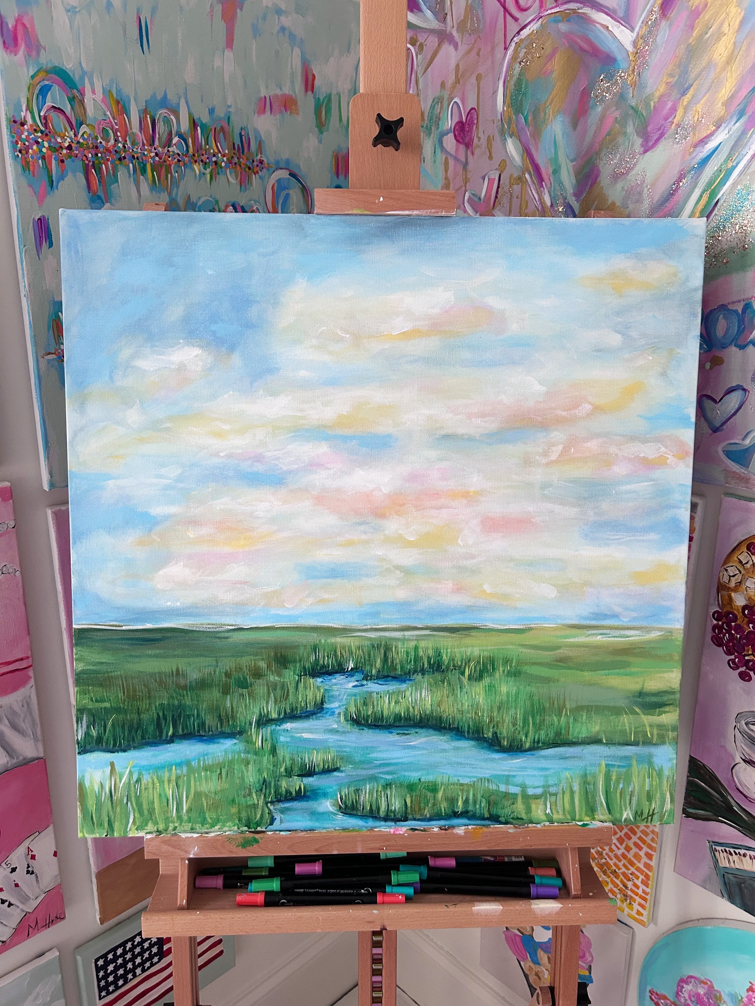 A landscape painting depicting a serene scene with a narrow, winding river flowing through lush green grass under a pastel-colored sky with scattered clouds.