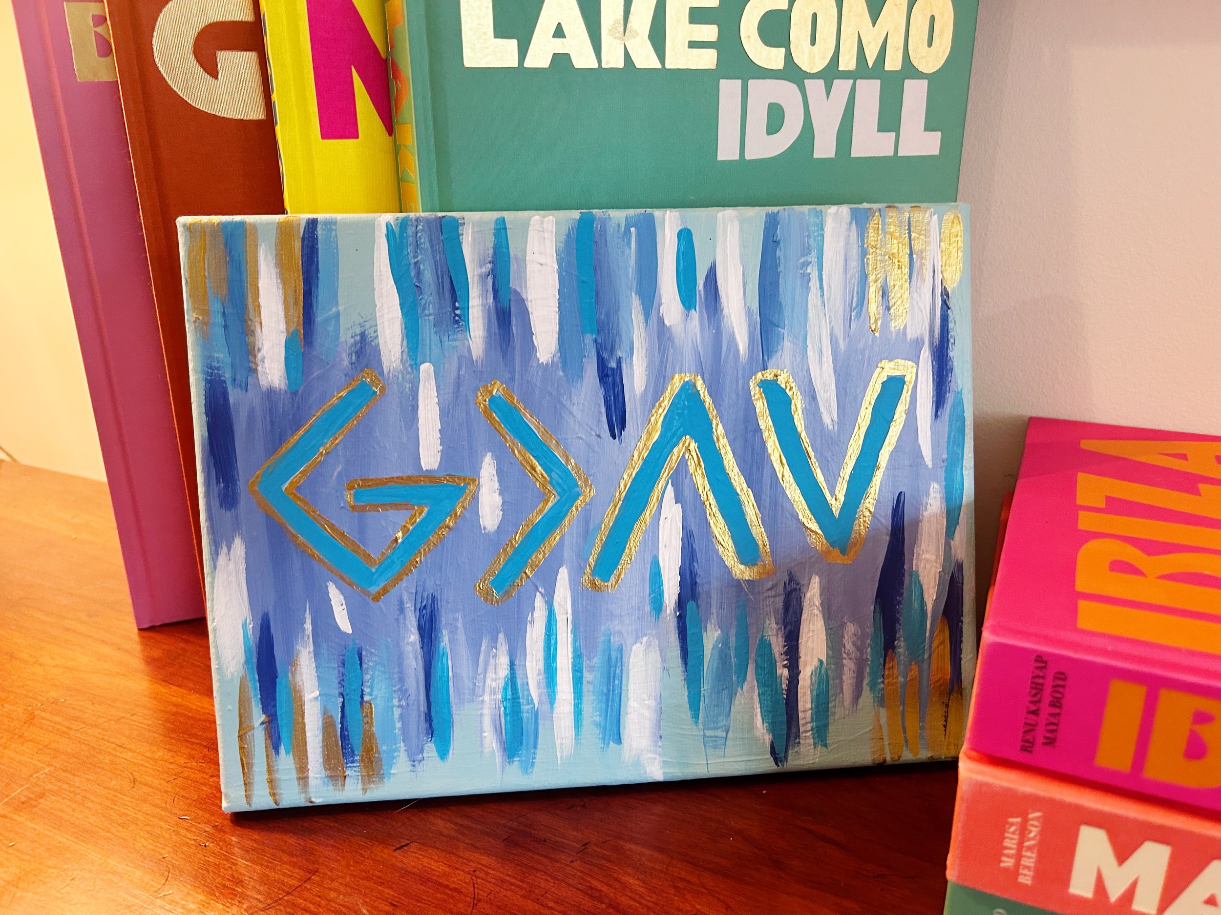 Colorful painted canvas with abstract blue and white brushstrokes and gold-lined arrows pointing left, right, up, down.