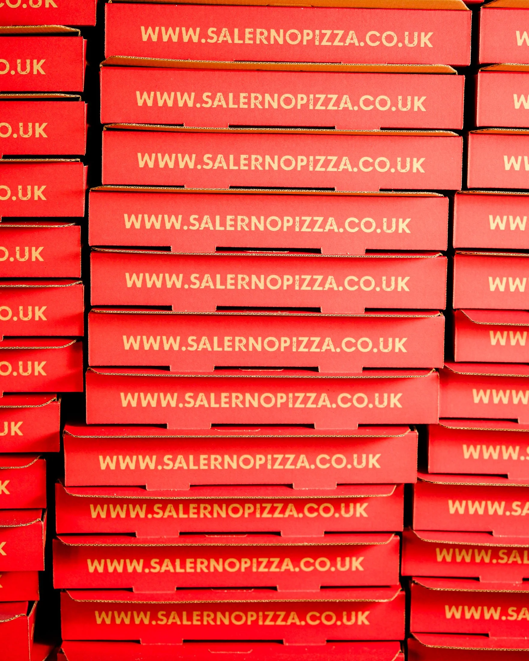 Front of a Salerno Pizza restaurant with glass windows and door, modern geometric design, and a menu display outside.