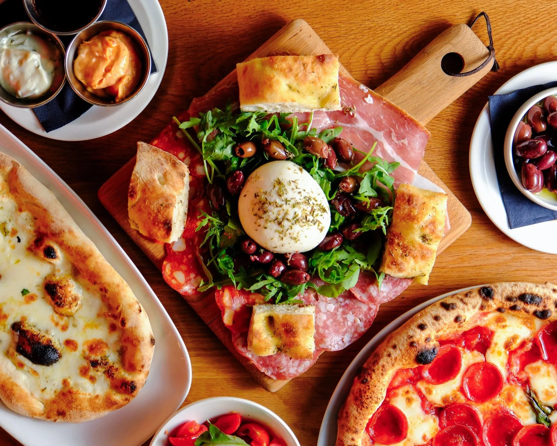 St James Quarter shopping center with two multi-story buildings and a glass-domed roof connecting them. People are walking and sitting in the outdoor area.