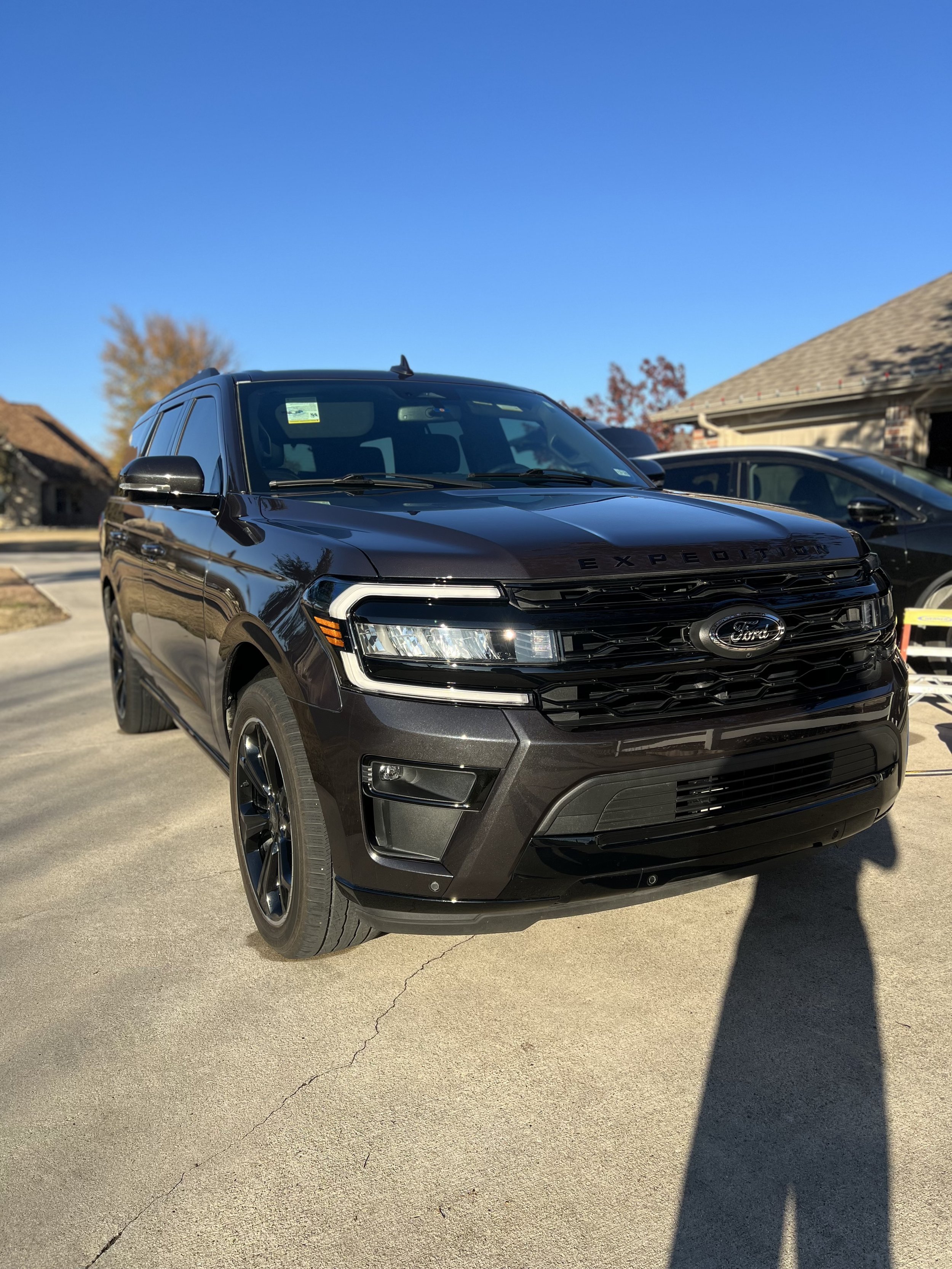 A black Ford Expedition SUV parked on a residential driveway on a sunny day.