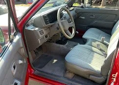 Interior of a red car showing gray fabric seats, steering wheel, and dashboard.