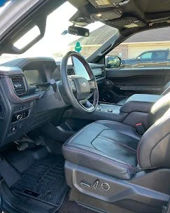 Interior of a vehicle showing the driver's seat, steering wheel, dashboard, and center console.