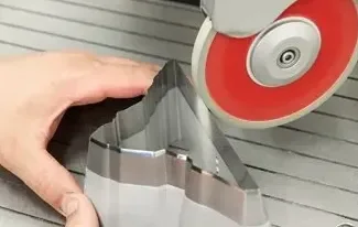 Close-up of a hand holding a metal cookie cutter on a baking sheet, with a red and silver kitchen tool nearby.