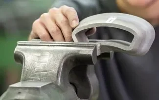 Close-up of a person's hand using a sander on a piece of metal.
