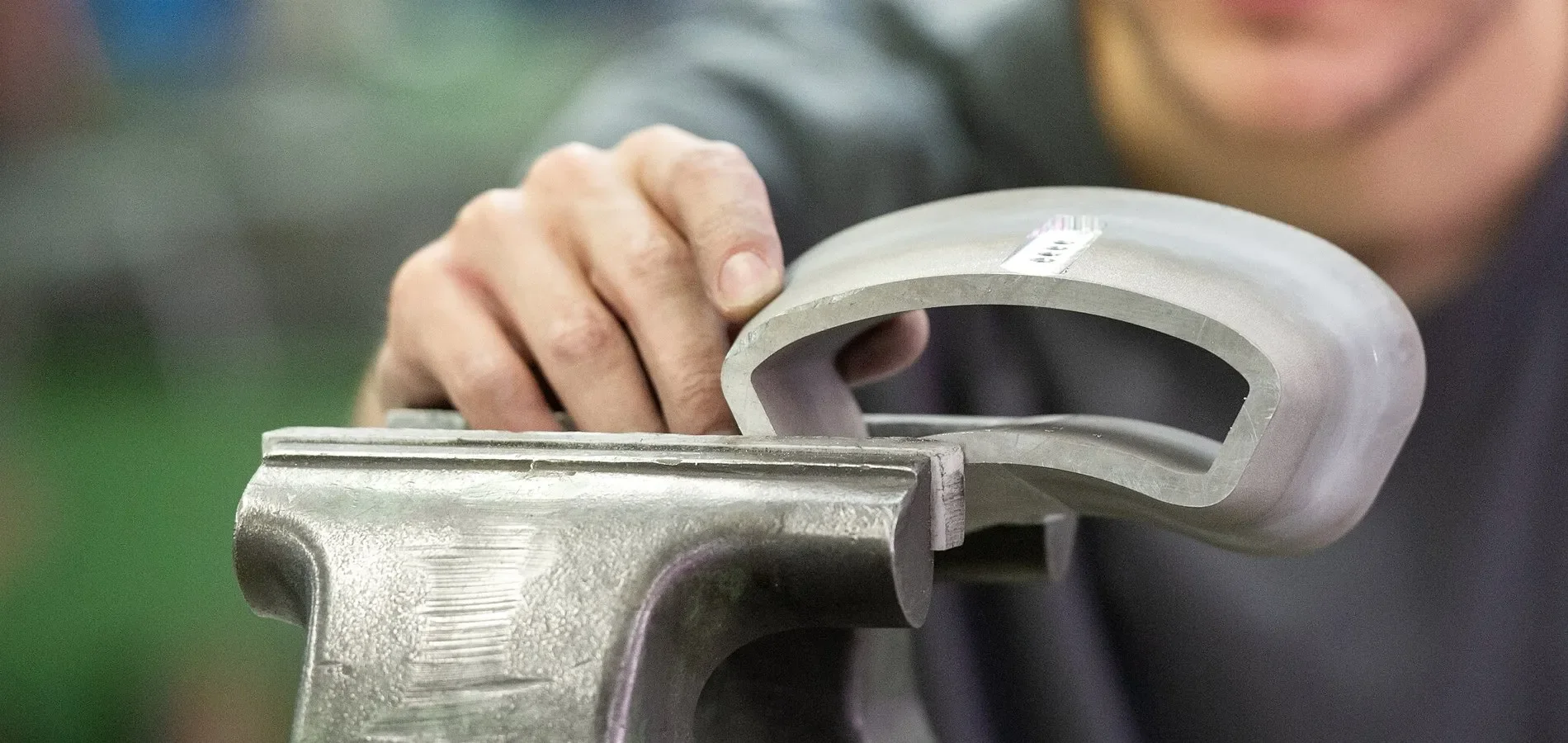 Person inspecting a metal machined part using their hand.