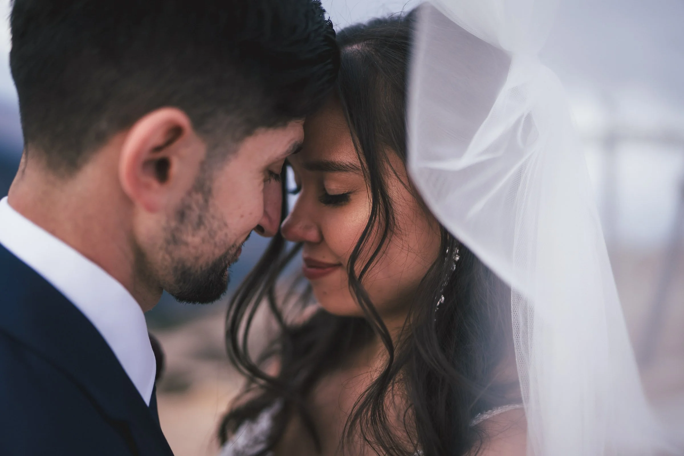 A close-up of a bride and groom with foreheads touching and eyes closed during their wedding ceremony.