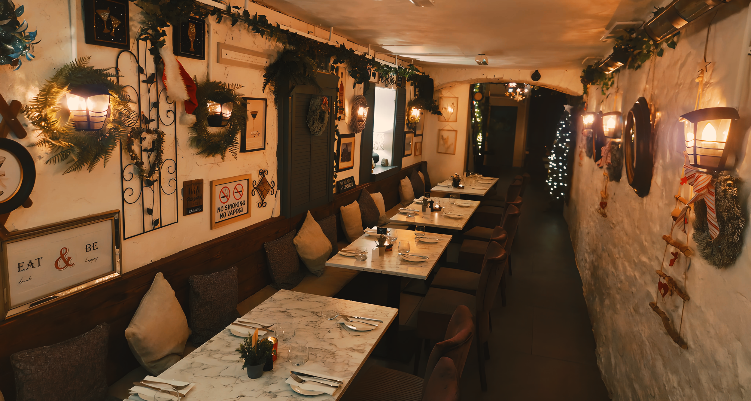 Cozy restaurant interior decorated with Christmas lights, wreaths, and festive ornaments, featuring marble tables, cushioned chairs, framed pictures, and warm wall sconces.