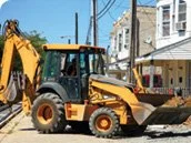 Yellow construction backhoe parked on a residential street
