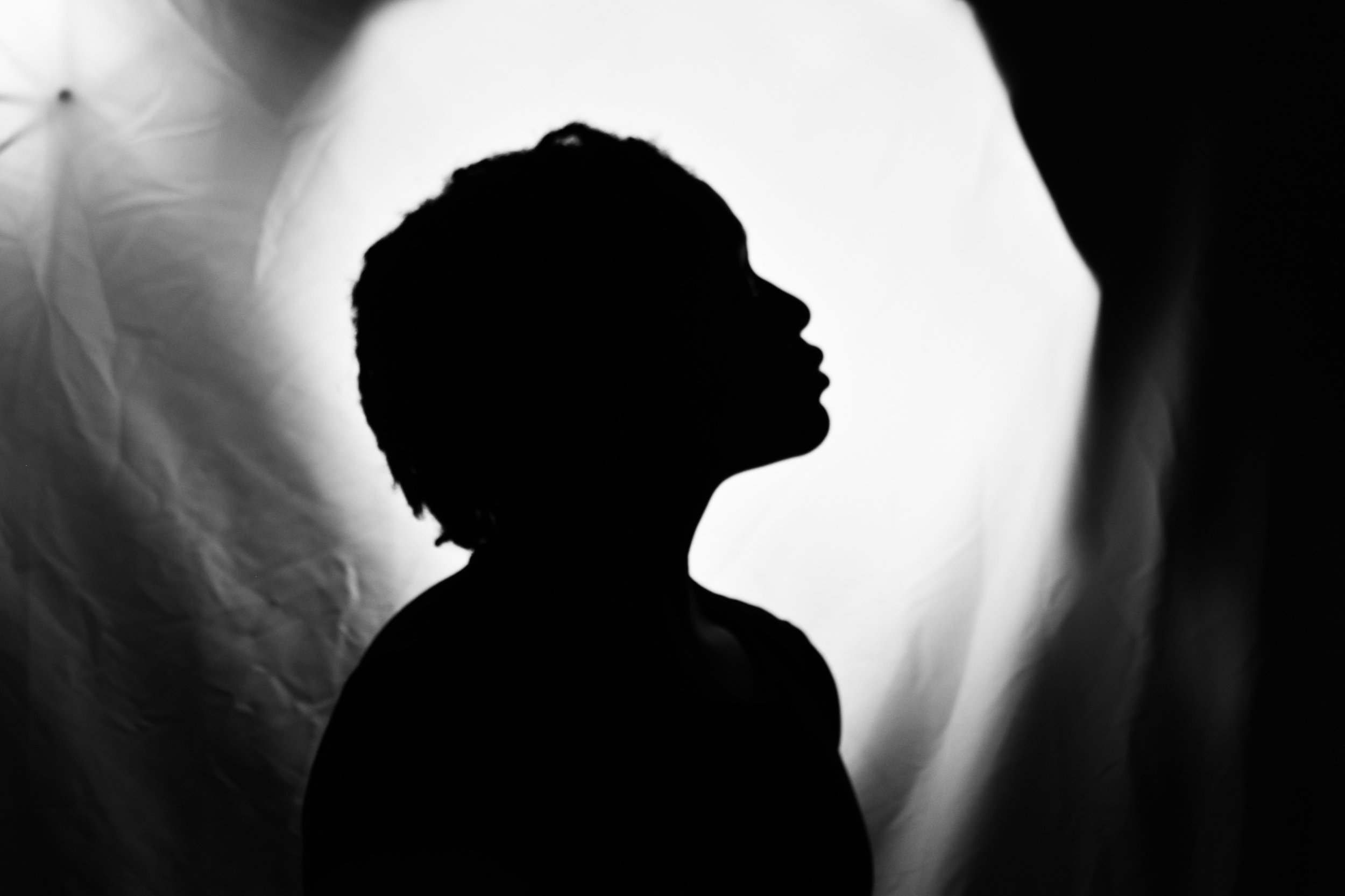 Silhouette of a person's profile in front of a backlit, textured background.