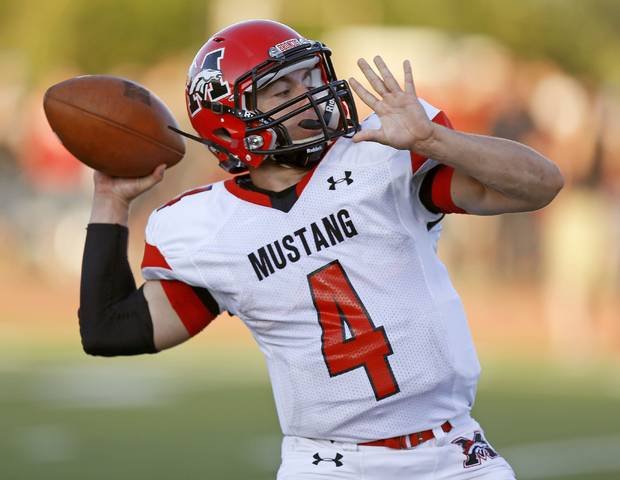 A football player in a white and red uniform with the number 4, wearing a red helmet and a black arm sleeve, preparing to throw a football during a game.