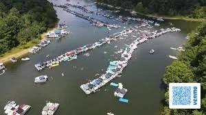 Aerial view of numerous boats and houseboats docked on a river surrounded by green trees.