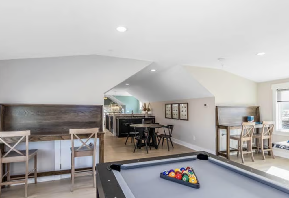 Living room with pool table, small dining table, bar-height chairs, and a window