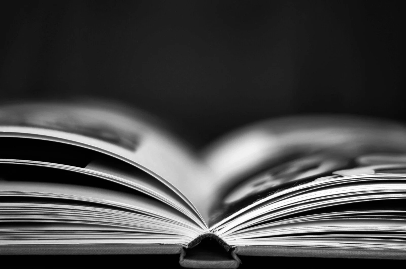 Hardcover book laid flat and opened halfway pictured from the bottom of the book looking into the spine in black and white
