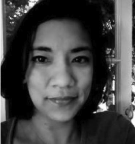 Black and white image of Regine Spectore looking straight to camera with a small smile.