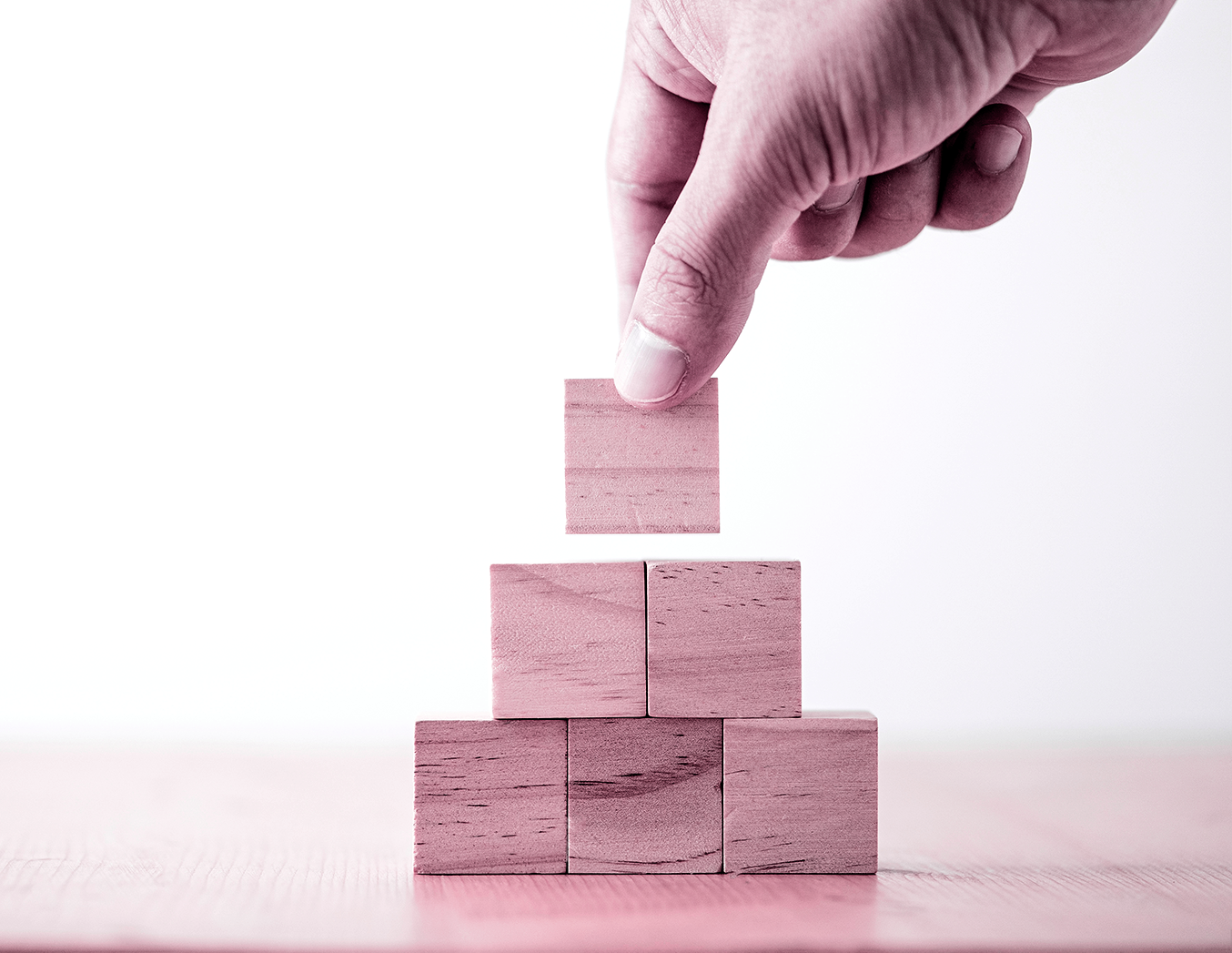 A hand places the final block on a stack of wooden blocks