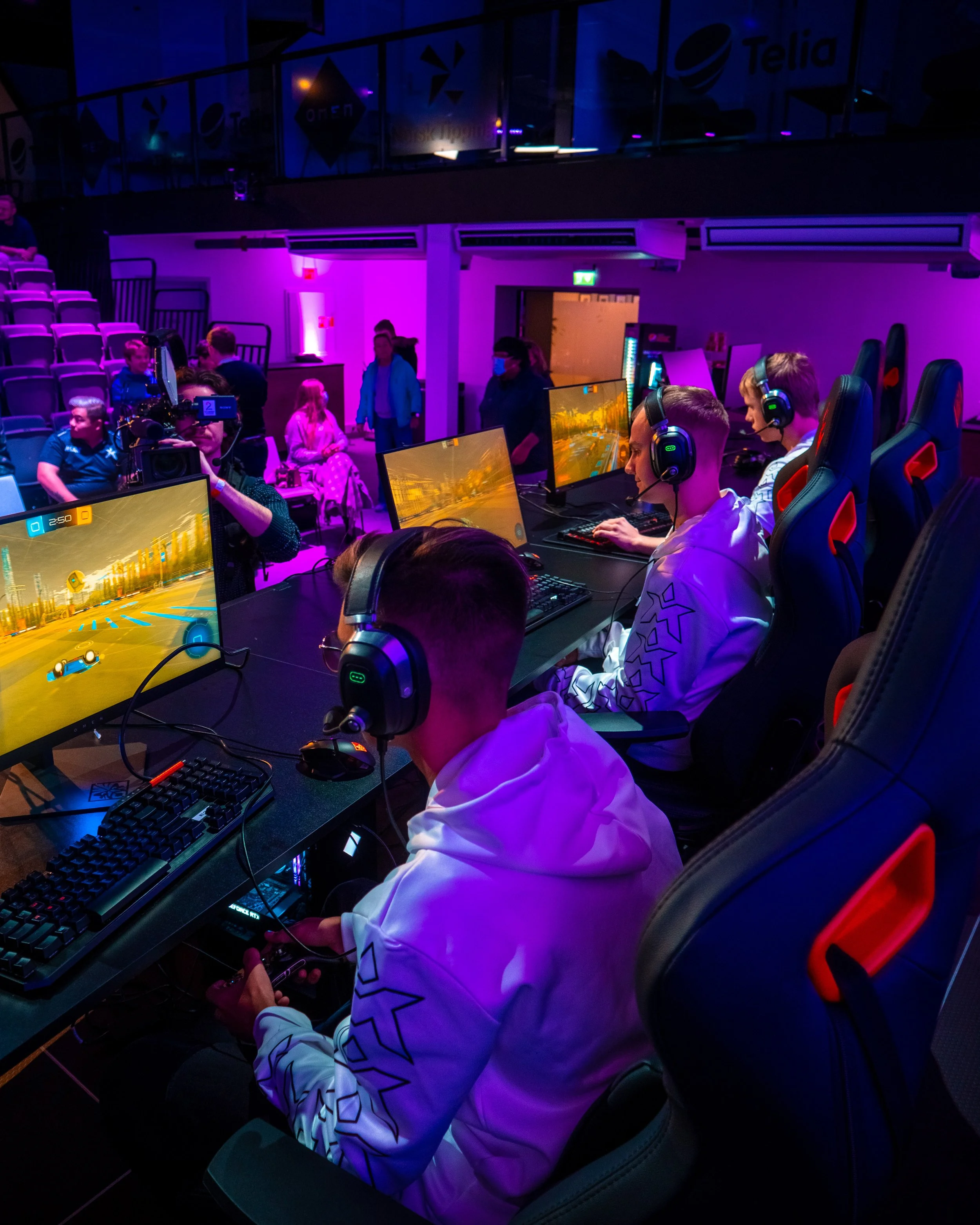 Ungdommer spiller dataspill i en gamingmesse under neonbelysning.