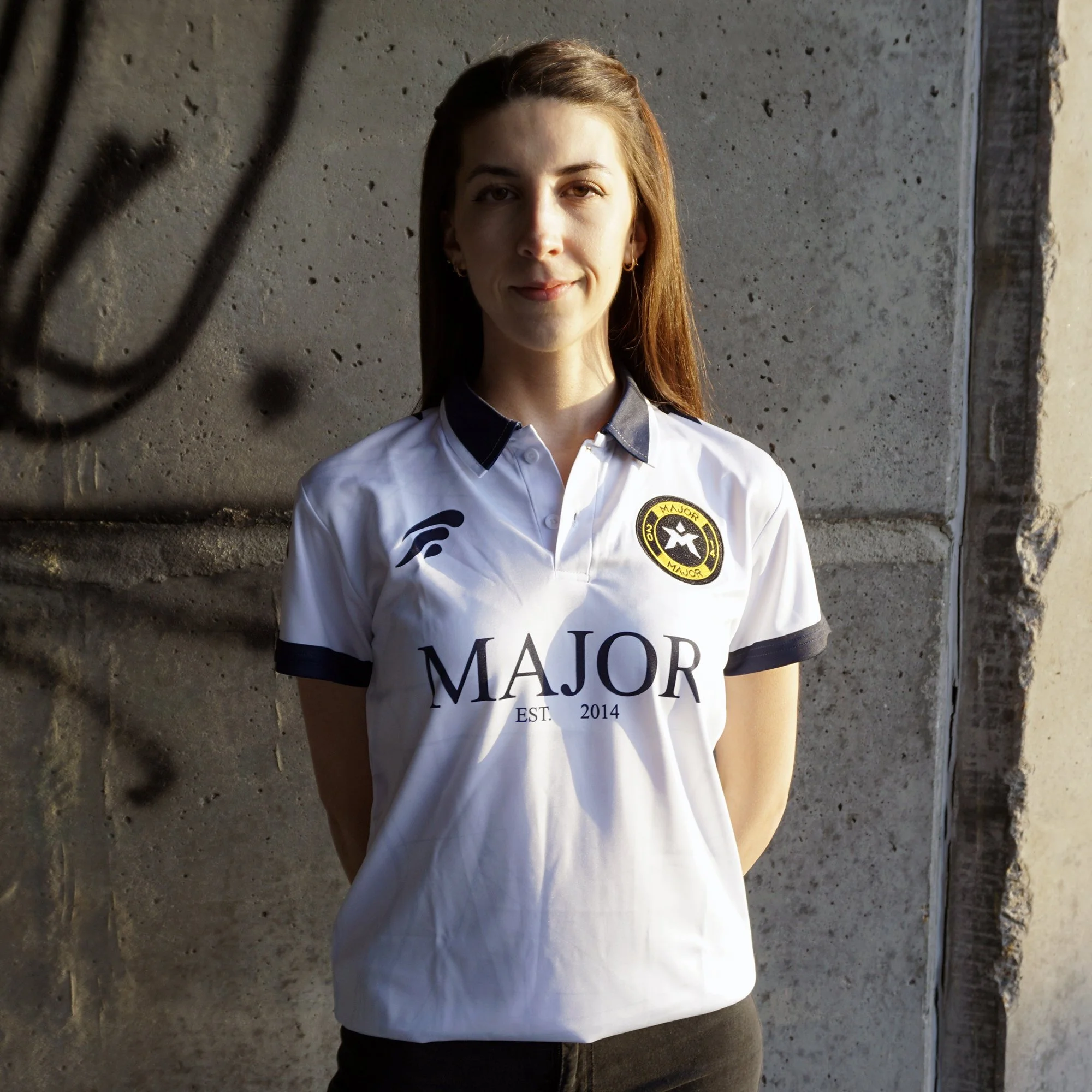 En kvinne kledd i en hvit sports T-skjorte med logoer og tekst.