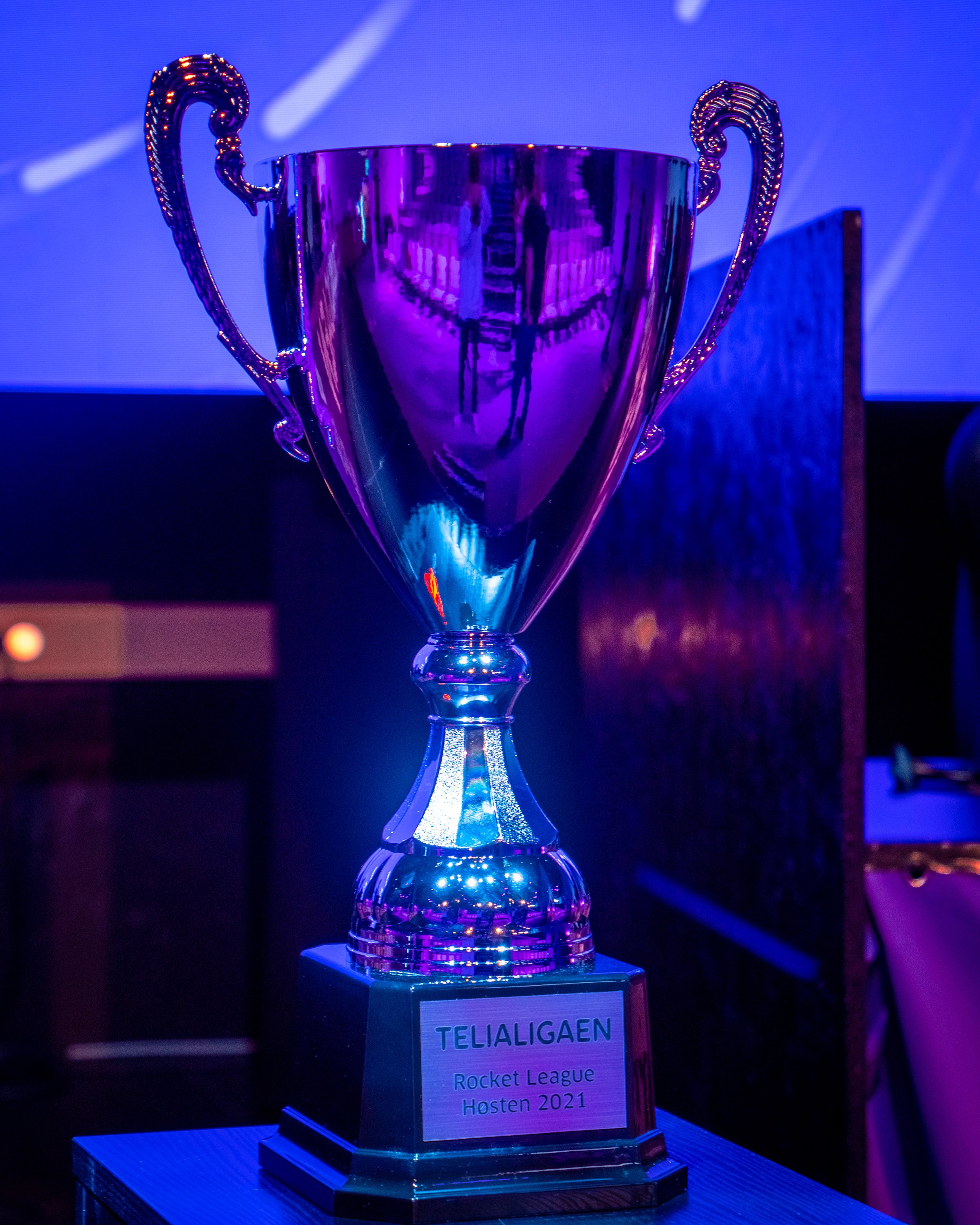 En pokal som vinner Trofe for Rocket League i høstsesongen 2021, plassert på et bord under blå belysning.