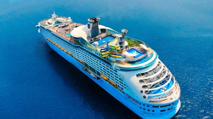 Aerial view of a Royal Caribbean cruise ship at sea, showcasing expansive decks, pools, and onboard amenities