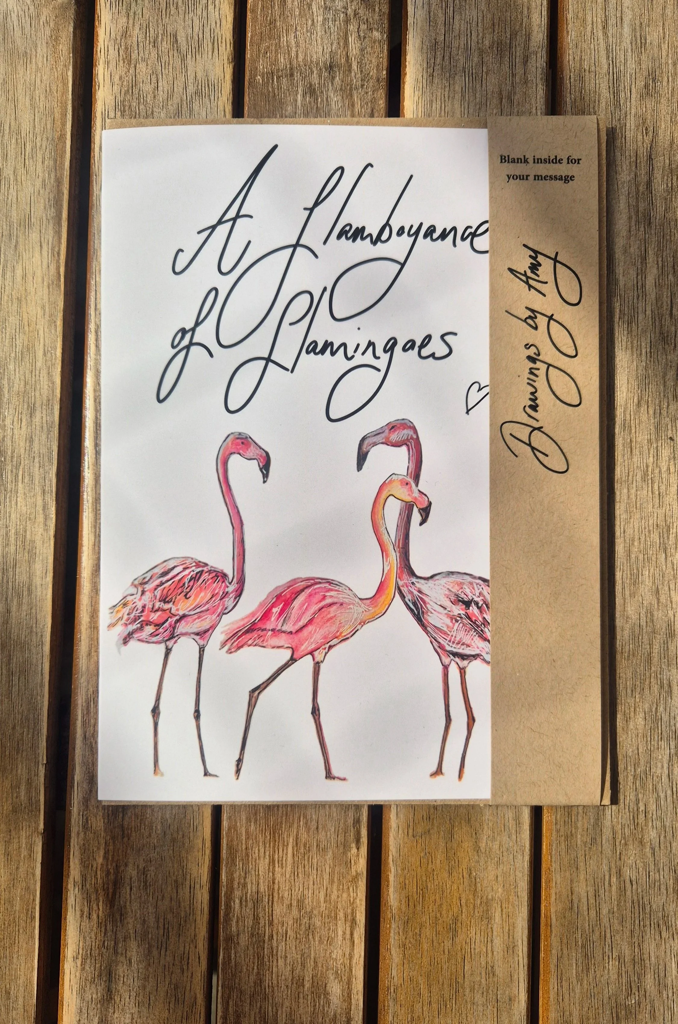 An image of a greetings card, with three flamingoes on the front