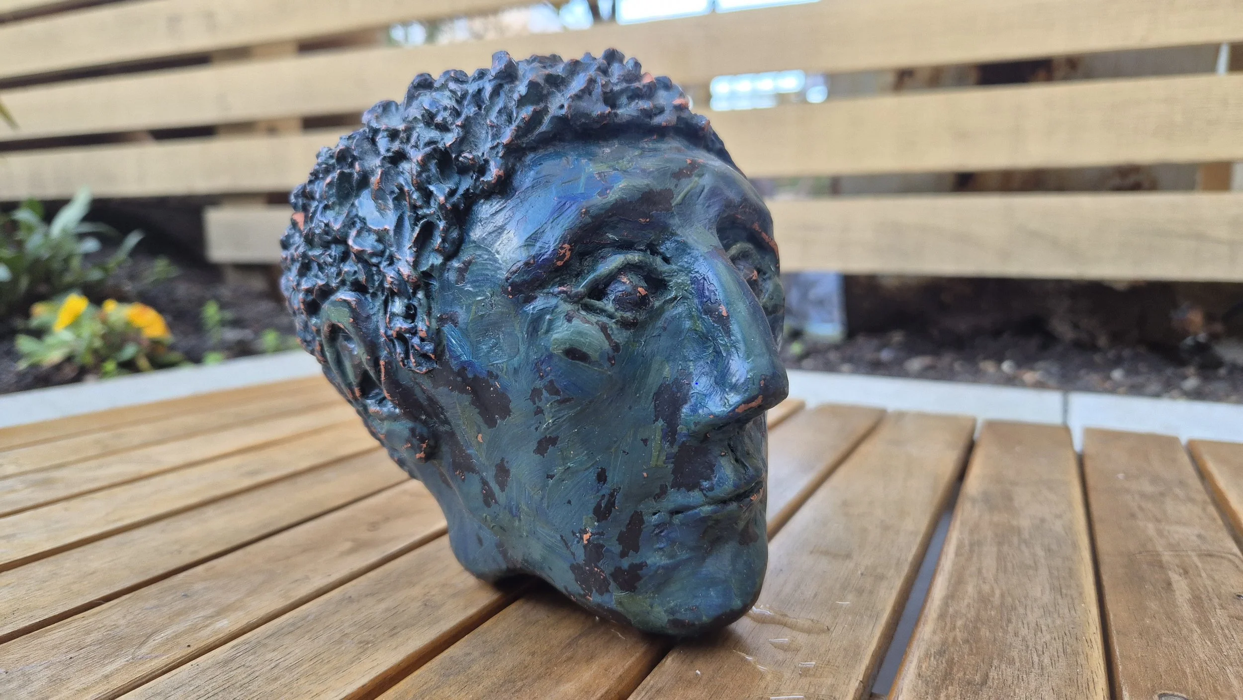 Image of a clay sculptural head on a wooden table