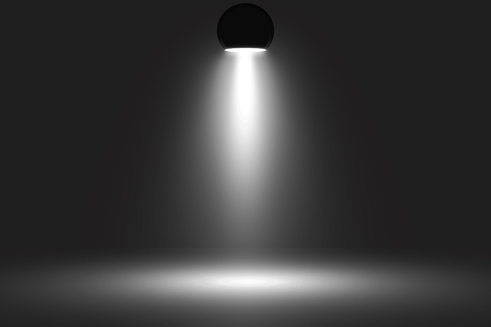 A spotlight shining down on a dark, empty floor in a black space.