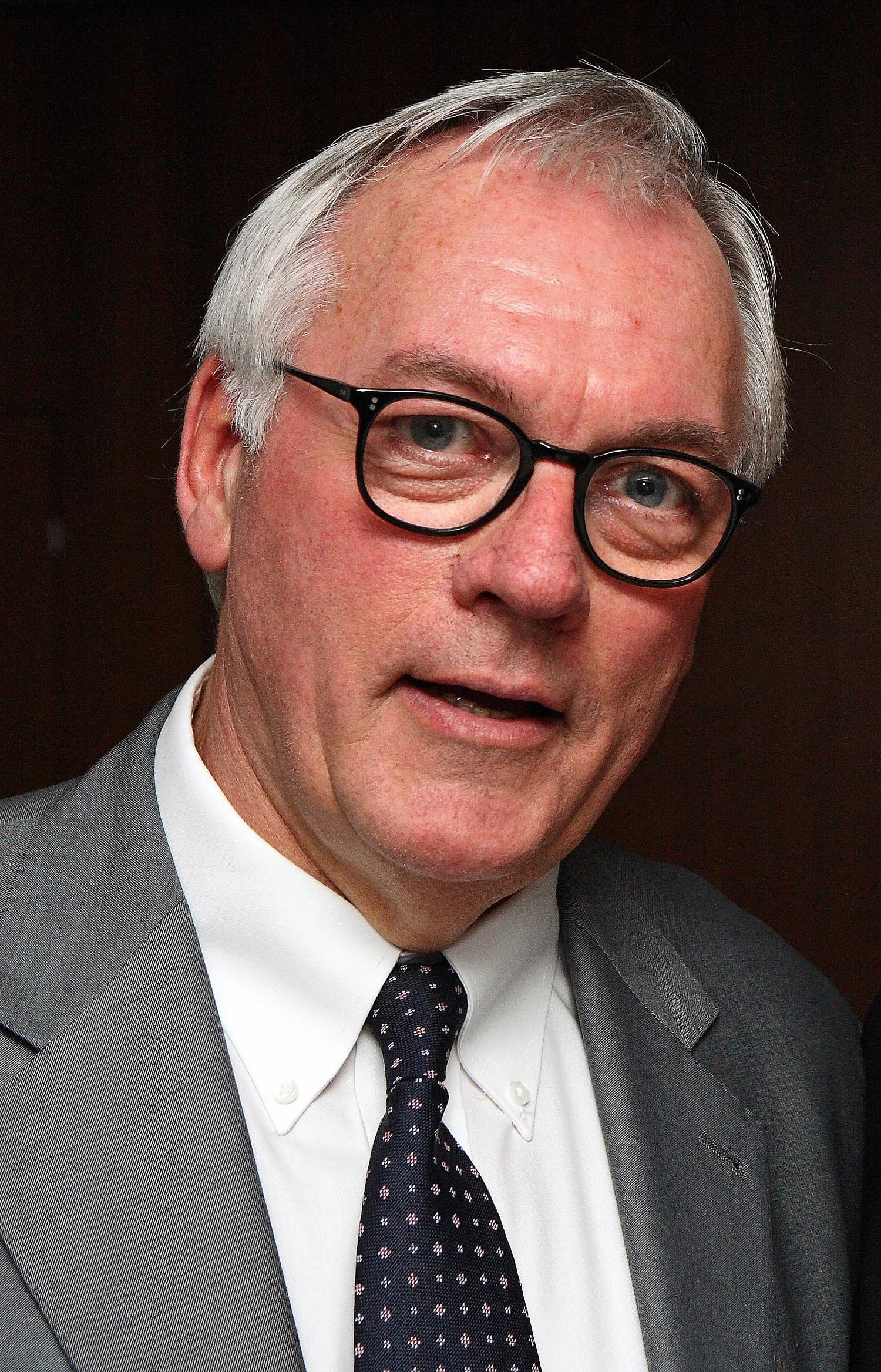 Carl Leighton-pope standing wearing a suit, smiling for the camera.