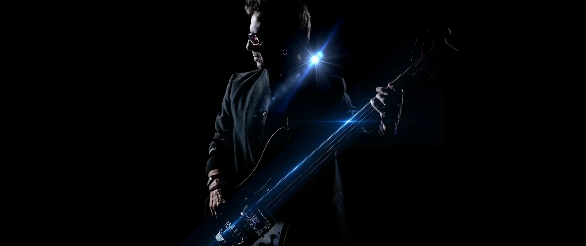 A person holding an electric guitar in a dark setting with bright blue light flares.